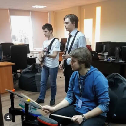 Три человека в офисе играют в Guitar Hero