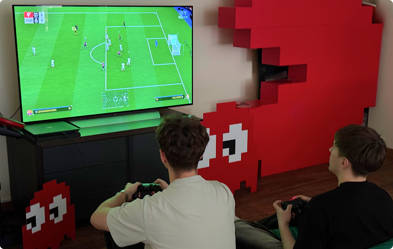 Мужчины перед монитором играют в Fifa на приставке