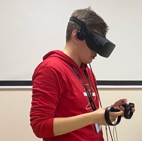 Мужчина в красном свитшоте взаимодействует с VR-гарнитурой